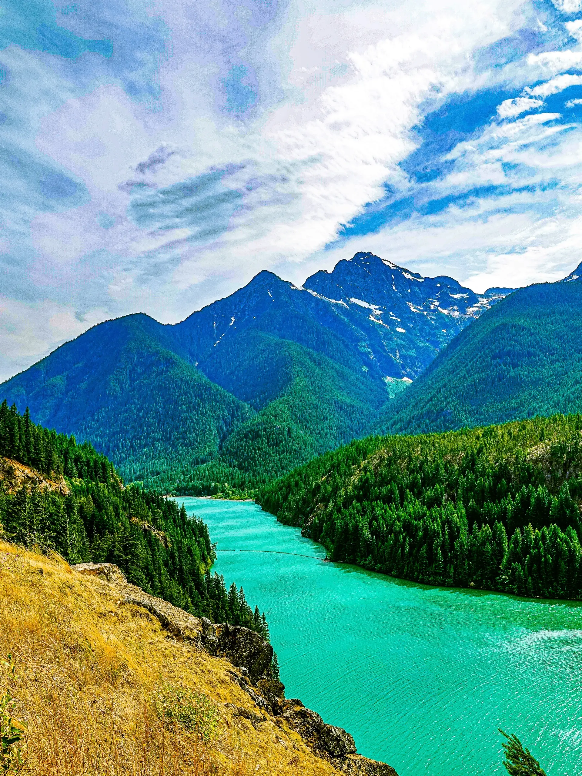 A turquoise glacial lake winding through the forested North Cascades of the Pacific Northwest